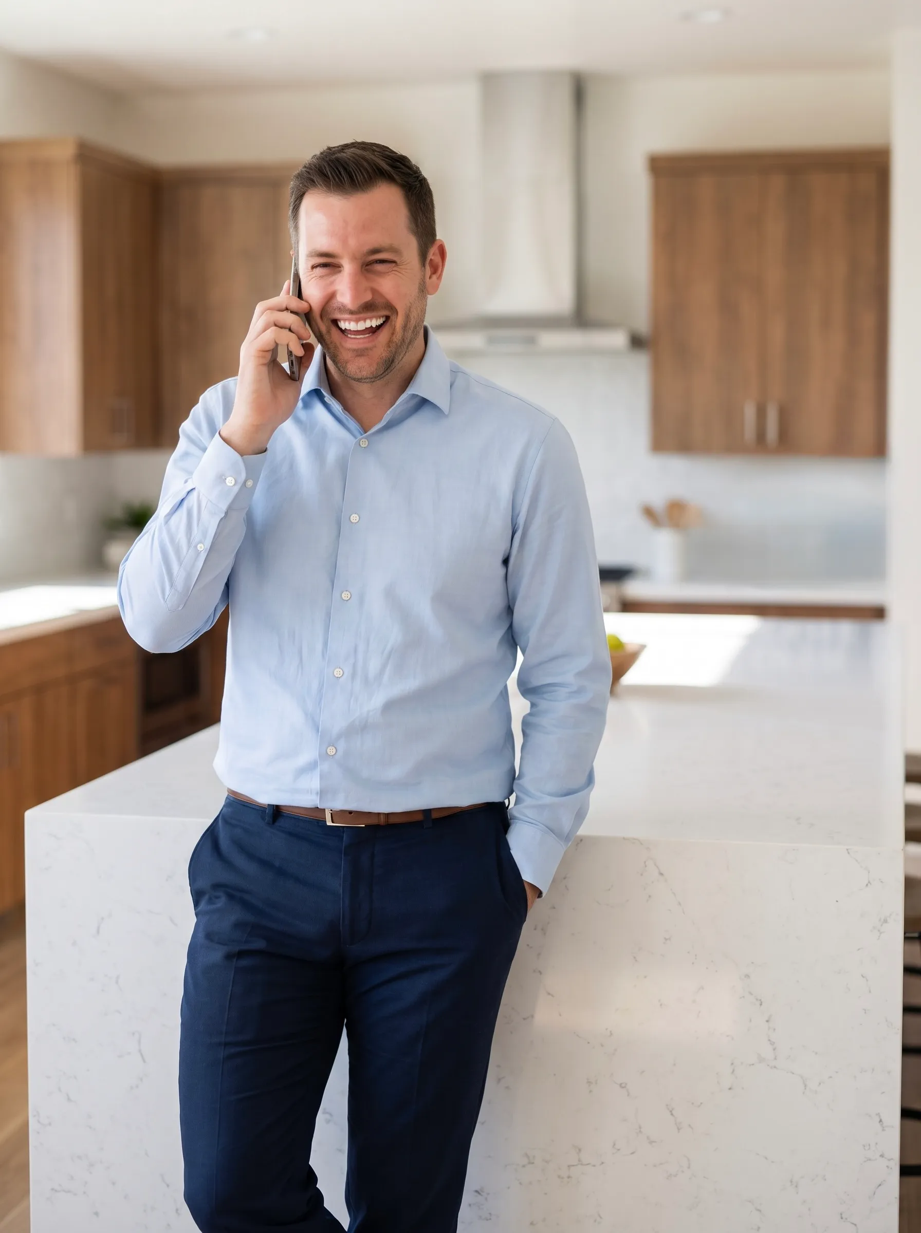 Corretor sorrindo ao telefone na cozinha de um imóvel